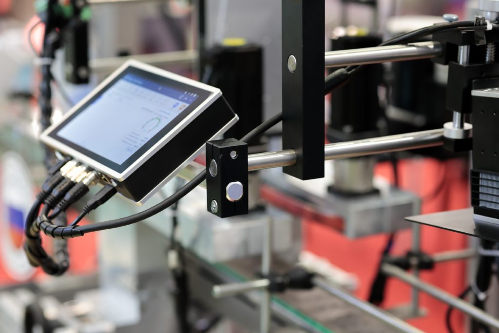 HMI touchscreens and sensors along a factory conveyor in operation.
