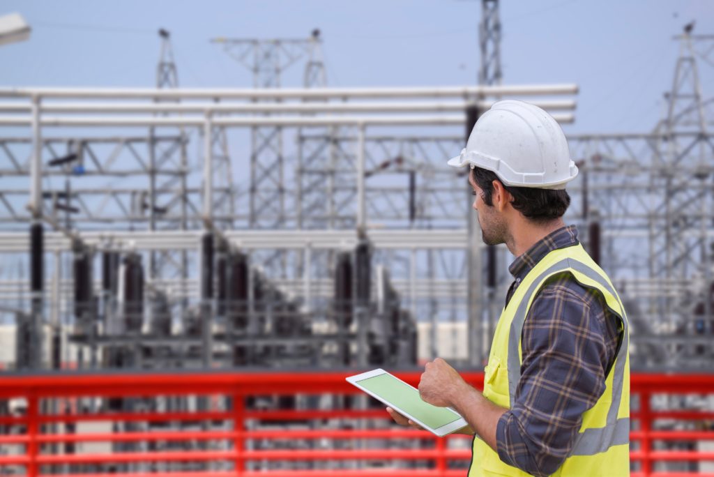 Jobsite Wi-Fi with foreman using a tablet — Divine Logic Clean-shaven foreman in PPE checks plans on a tablet near a jobsite Wi-Fi antenna.