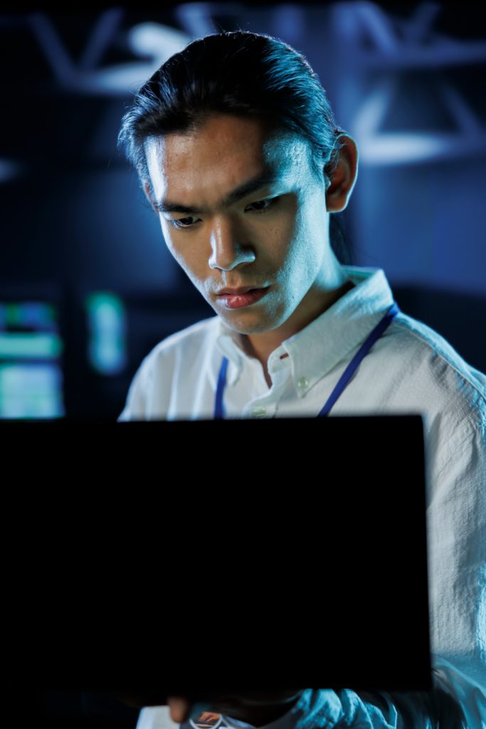 Managed IT consult with local expert—Divine Logic Clean-shaven IT consultant reviews fixes with a client at a laptop; server rack softly in background.