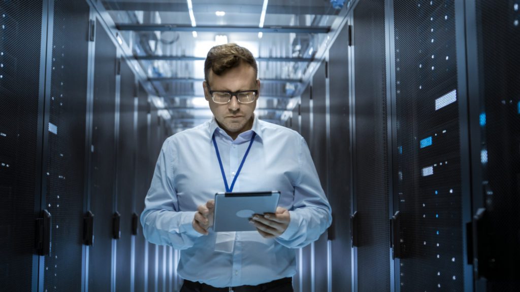 Preventive rack inspection protects hardware investment Technician in tie checks a server rack with a tablet during preventive maintenance.
