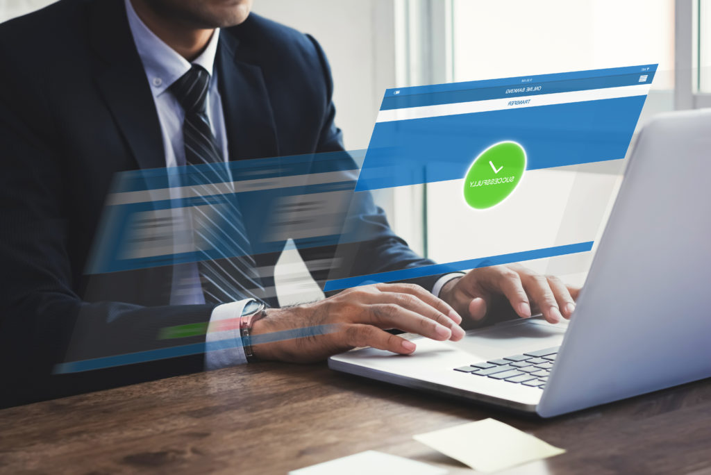Businessman,Successfully,Transferring,Money,With,Internet,Online,E-banking,On,Laptop Technician in tie begins a secure remote login on dual monitors in a modern office.